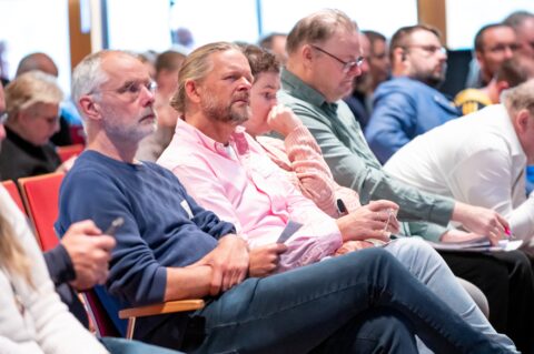 Aanwezigen zitten in de zaal tijdens het MZSW-congres aandachtig te luisteren