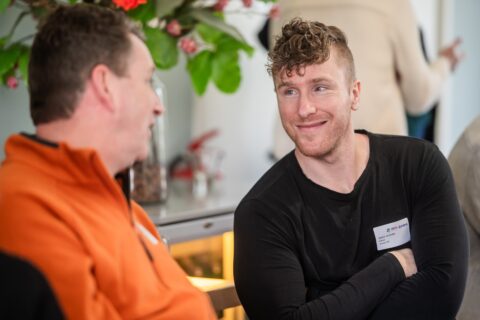 Twee personen glimlachen naar elkaar tijdens een gesprek.