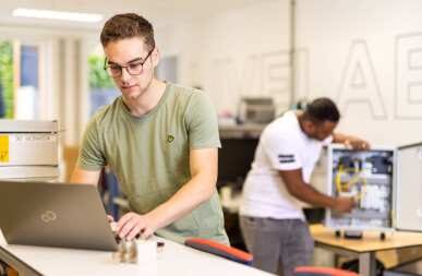 Medewerker werkt in techniekzaal aan de laptop.