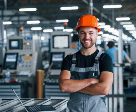 Man met helm blij aan het werk in productie-omgeving